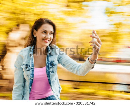 young beautiful woman taking selfie outdoor on the carousel