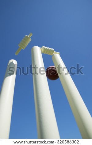 Ball knocks the bails off the stumps with blue sky