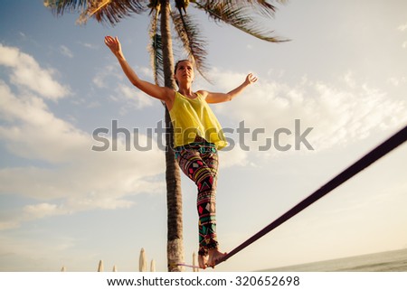 teenage girl  balancing on slackline with sky view on the beach Royalty-Free Stock Photo #320652698