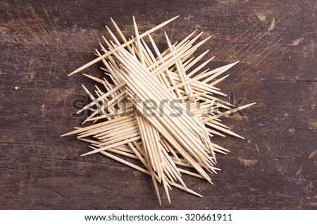 Many toothpicks tightly piled together facing different directions on dark wooden surface.