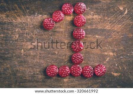 the number one shaped by raspberry hard candy on wooden surface.