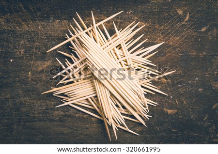 Many toothpicks tightly piled together facing different directions on dark wooden surface.