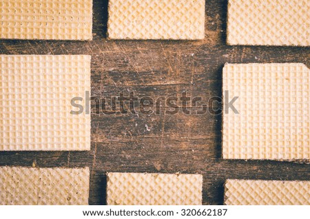 Closeup square cookies lined up on wooden surface crating an artistic pattern, middle snack is missing.
