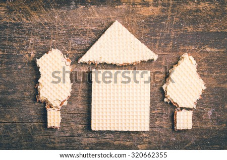 Simple house with trees outside design illustrated by using cookies on wooden surface.