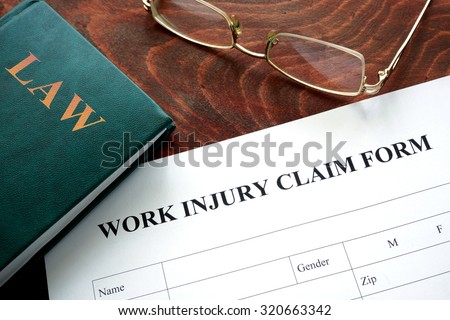 Work injury claim form on a wooden table. Royalty-Free Stock Photo #320663342