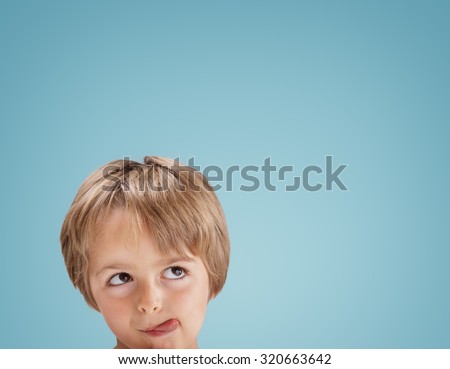 Boy with tongue out licking his lips looking up at copy space for a message or product placement
