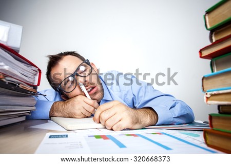 Funny photo of businessman with beard wearing shirt and glasses. Overworked businessman sleeping at table full of documents with pen in his nose. Isolated on white background