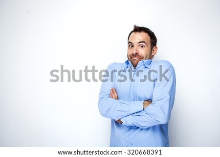 Funny photo of businessman with beard wearing shirt. Businessman looking at camera and shrugging his shoulders with discomfort. Isolated on white background
