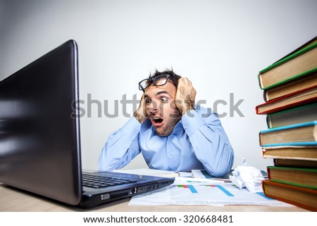 Funny photo of businessman with beard wearing shirt and glasses. Overworked and angry businessman working with laptop at table full of documents. Isolated on white background
