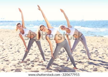 A picture of a group of women practising yoga on the beach