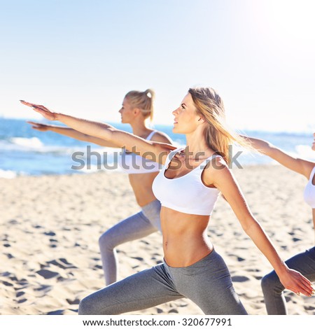 A picture of a group of women practising yoga on the beach
