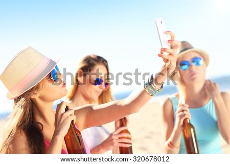 A picture of a group of friends drinking beer and taking selfie on the beach