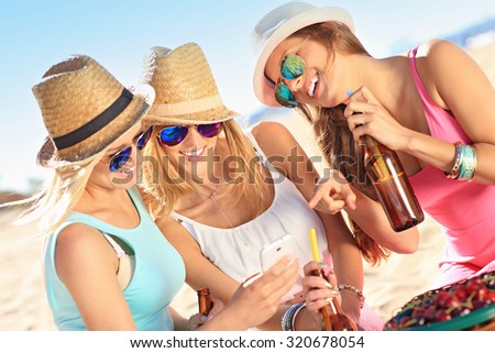 A picture of a group of friends drinking beer and texting on the beach
