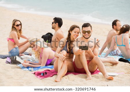 Smiling friends doing selfie at sea shore on vacation