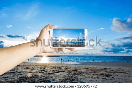 Man photographed sunset at the beach with his Smartphone, Beautiful , sharp images and realistic, Phuket Thailand.