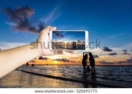 Man photographed sunset at the beach with his Smartphone, Beautiful , sharp images and realistic , Phuket Thailand.
