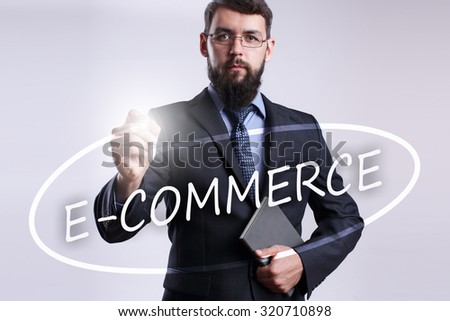 Businessman writing "E-commerce" with marker on transparent board.