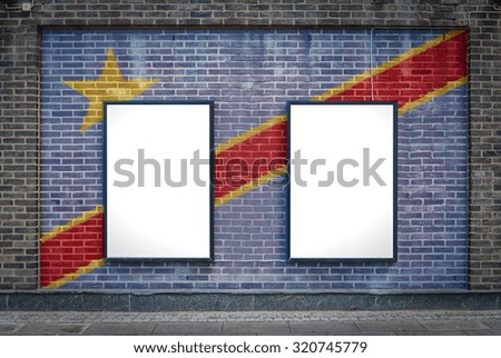 Two blank billboards attached to a buildings exterior brick wall which has a Congo Kinshasa flag painted on it.
