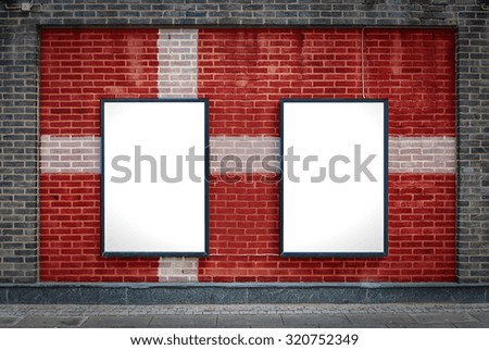 Two blank billboards attached to a buildings exterior brick wall which has a Danish flag painted on it.