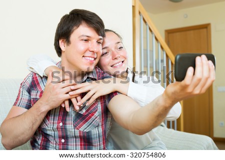 Cheerful young couple taking selfie with a smartphone