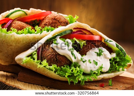 Falafel and fresh vegetables in pita bread on wooden table Royalty-Free Stock Photo #320756864