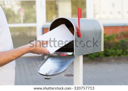 Close-up Of Person Putting Stack Of Letters In Mailbox Royalty-Free Stock Photo #320757713