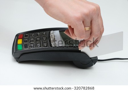 The girl holds in hand a credit card in front of the terminal in shop. A white credit card without image. Payment by a credit card in the terminal