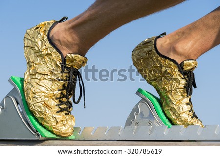 Gold running shoes close-up of an athlete in the starting blocks on a race track