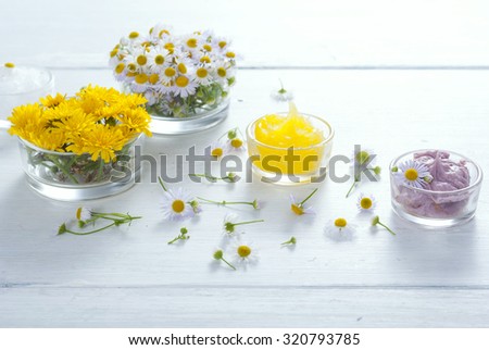 cosmetic product samples with herbal flowers on white wooden table 