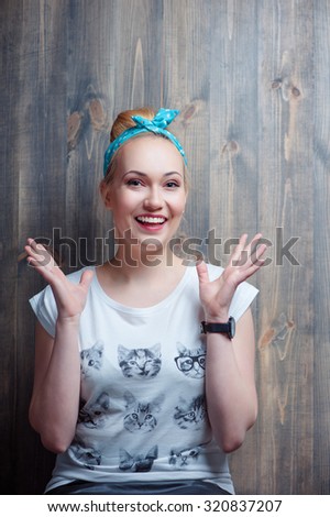 What a surprise! Young attractive amazed woman gesturing against wooden wall.