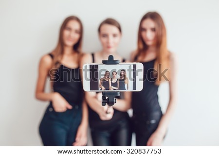 3 Beautiful young girls taking a photo with selfie stick