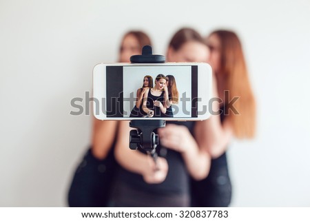 3 Beautiful young girls taking a photo with selfie stick
