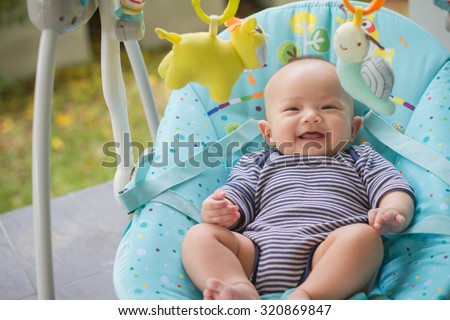 Newborn baby sleeping in a bouncer in the garden Royalty-Free Stock Photo #320869847