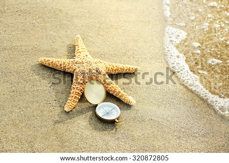 Compass with sea star on sand beach background