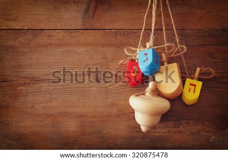 image of jewish holiday Hanukkah with wooden colorful dreidels (spinning top) hanging on a rope over wooden background 