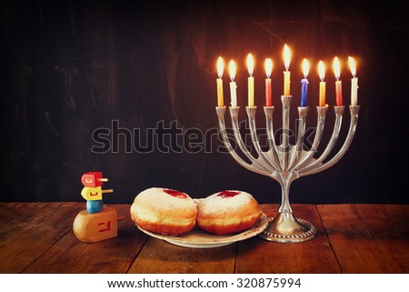 image of jewish holiday Hanukkah with menorah (traditional Candelabra), donuts and wooden dreidels (spinning top). retro filtered image 