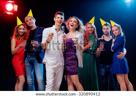 Party and celebration. Group of happy smiling friends having fun together, singing karaoke in the nightclub.