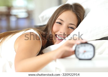 Happy woman waking up and turning off the alarm clock having a good day Royalty-Free Stock Photo #320922914