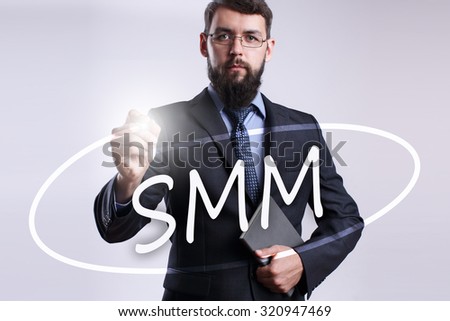 Businessman writing "SMM" with marker on transparent board.