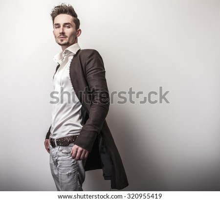 Elegant young handsome man in long stylish coat. Studio fashion portrait.
