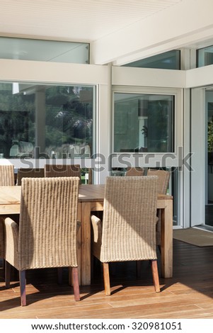 veranda of a modern house, wicker chairs and wooden table