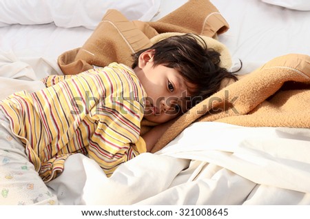 Little boy sleeping on bed in morning sun Shines. Royalty-Free Stock Photo #321008645