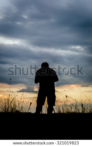 Silhouette of photographer taking pictures of beautiful sunset