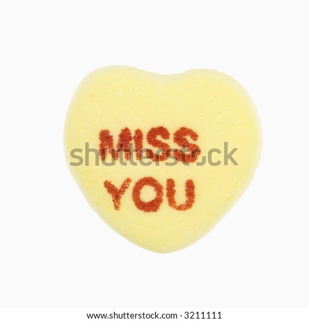 Yellow candy heart that reads miss you against white background.