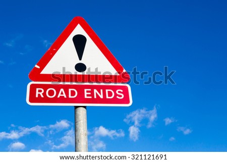 Red and white triangular road sign with warning that the Road Ends  against a partly cloudy sky background