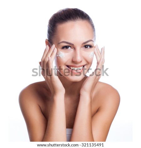beautiful model applying cosmetic cream treatment on her face on white Royalty-Free Stock Photo #321135491