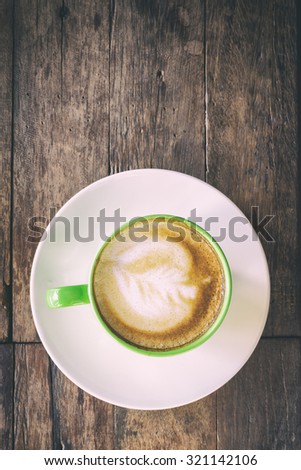 Top view art hot coffee in green cup with coffee beans on wood background