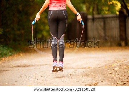 Close up of woman feet jumping, using skipping rope in park Royalty-Free Stock Photo #321158528