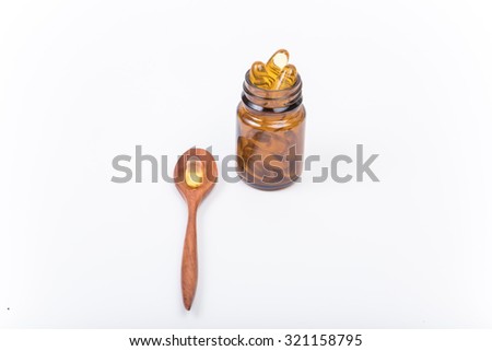 wooden spoon fish oil capsules and bottle with white background