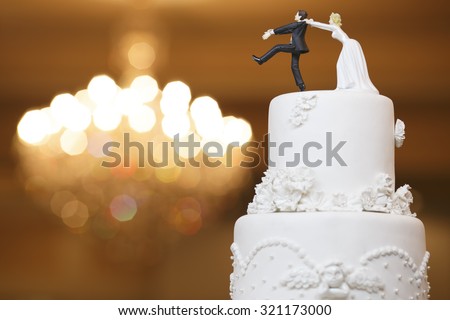 wedding bride and groom couple doll in funny action on wedding cake Royalty-Free Stock Photo #321173000